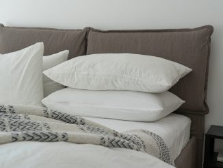 Ny redt seng med grå puder og hvide lagener