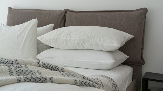 Ny redt seng med grå puder og hvide lagener